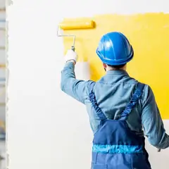 Baretli ustanın rulo ile beyaz duvarı sarıya boyaması